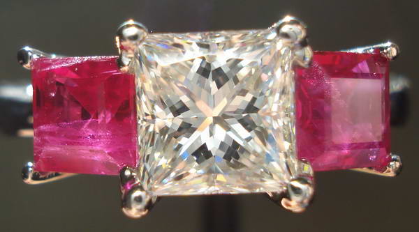 three stone diamond ring with white center diamond and ruby side stones